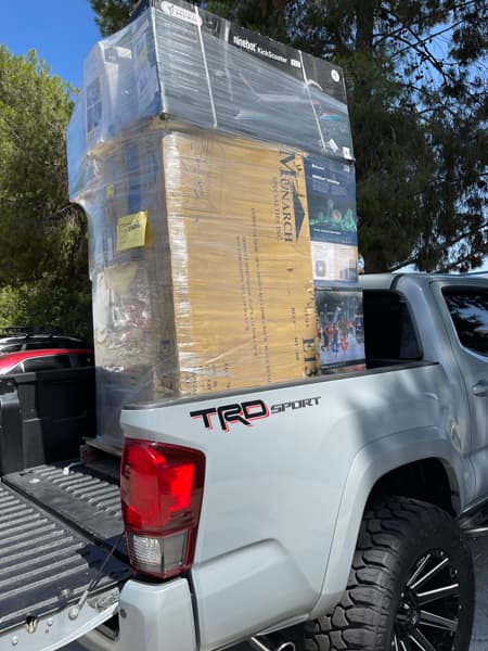 Picture of a wrapped pallet with a tower of goods on the back of a pick-up truck